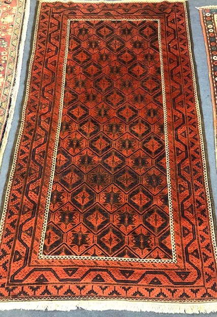 A Belouch red ground rug 204 x 115cm